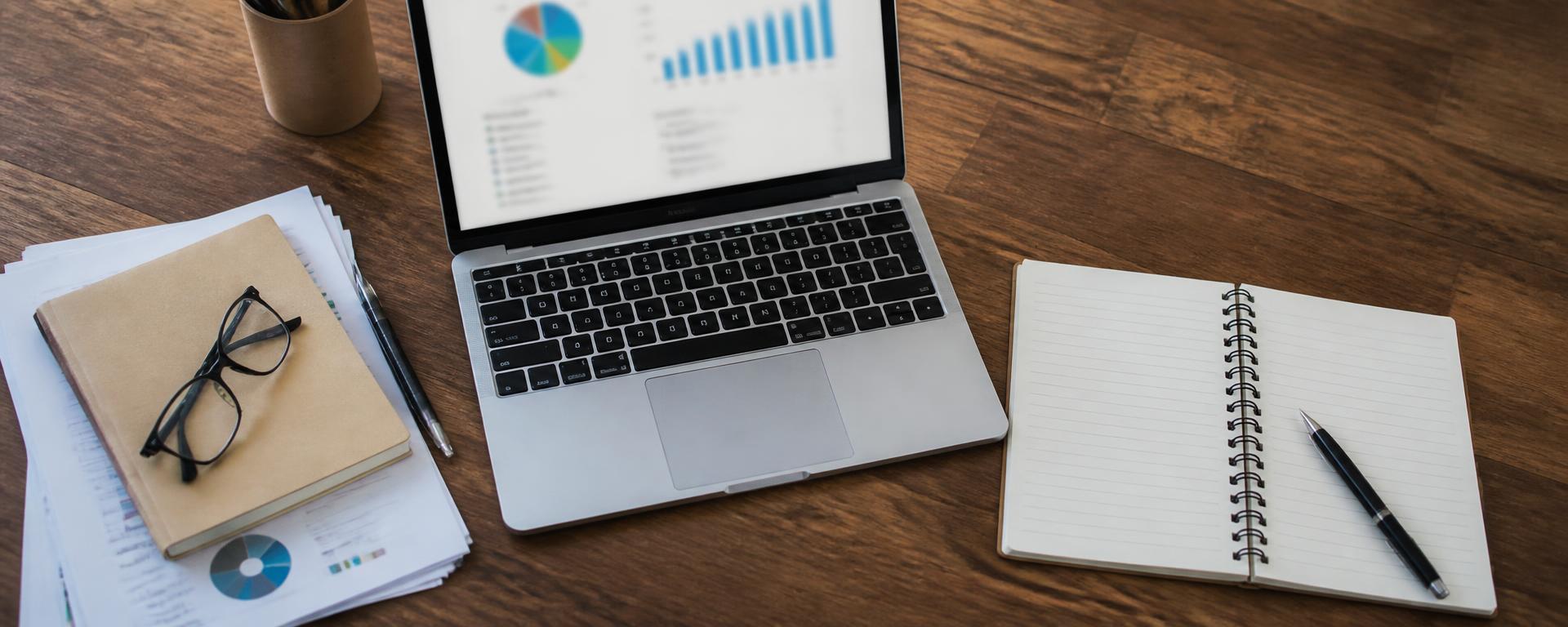 Printed web design guides, checklists and an analytics dashboard on a laptop